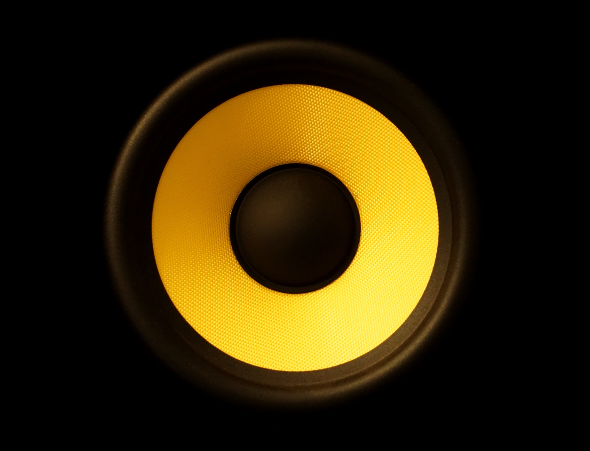 haut-parleur noir avec intérieur jaune et centre noir, sur un fond noir